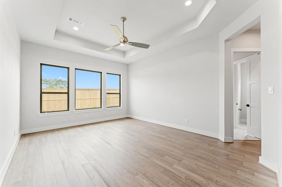 Primary Bedroom with Engineered Wood Flooring, Coffered Ceiling, and Fan.