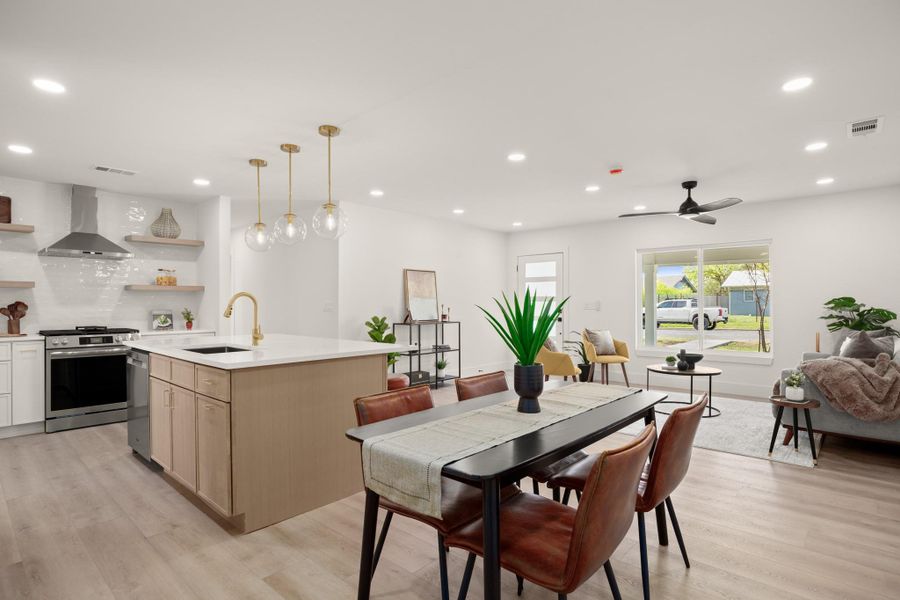 Kitchen featuring open shelves, stainless steel appliances, a center island with sink, light wood finish cabinets, and light wood-type flooring
