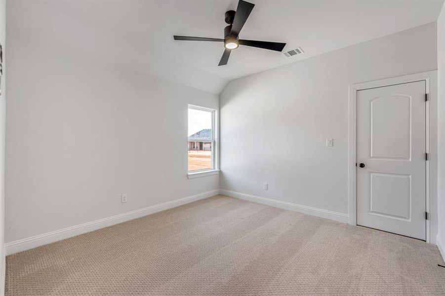 Spare room featuring light carpet, ceiling fan, and lofted ceiling