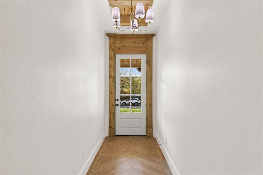 Doorway to outside featuring baseboards and a chandelier