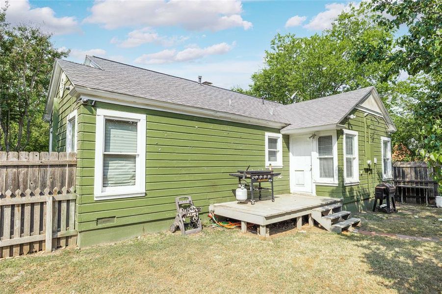 Back of house featuring a shingled roof and a wooden deck Back of house featuring a shingled roof and a wooden deck