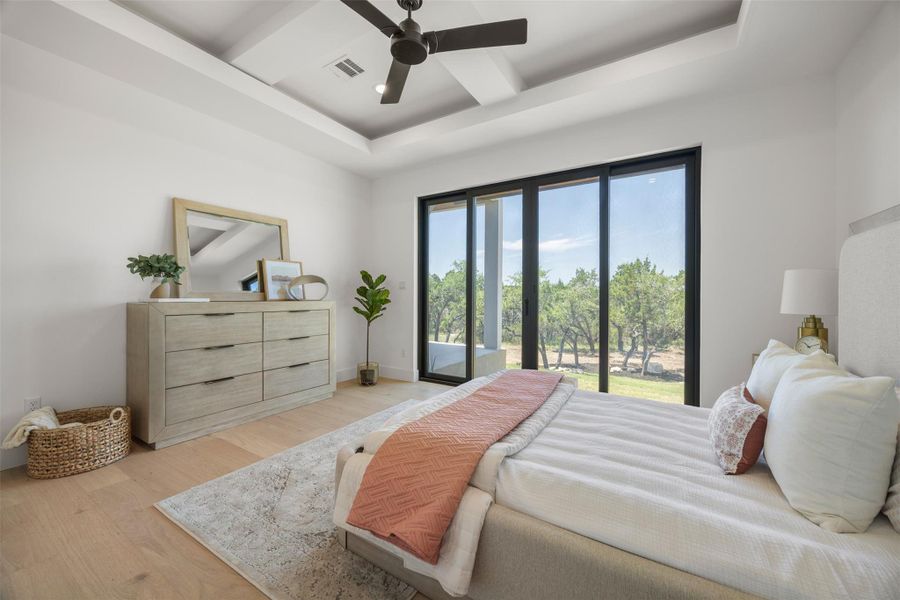 A tranquil bedroom retreat features a recessed ceiling, rich hardwood flooring, and direct access to outdoor serenity.