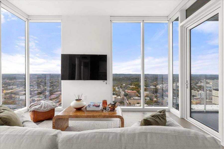 A bright, elevated living space offering uninterrupted vistas through full-height windows and direct access to the terrace.