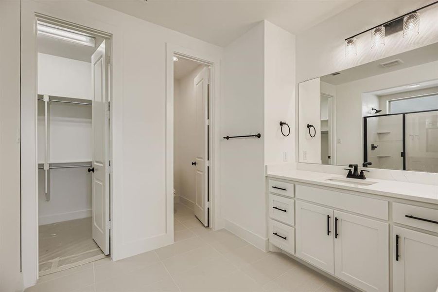 Bathroom featuring vanity, a stall shower, light tile patterned flooring, and a walk in closet Bathroom featuring vanity, a stall shower, light tile patterned flooring, and a walk in closet