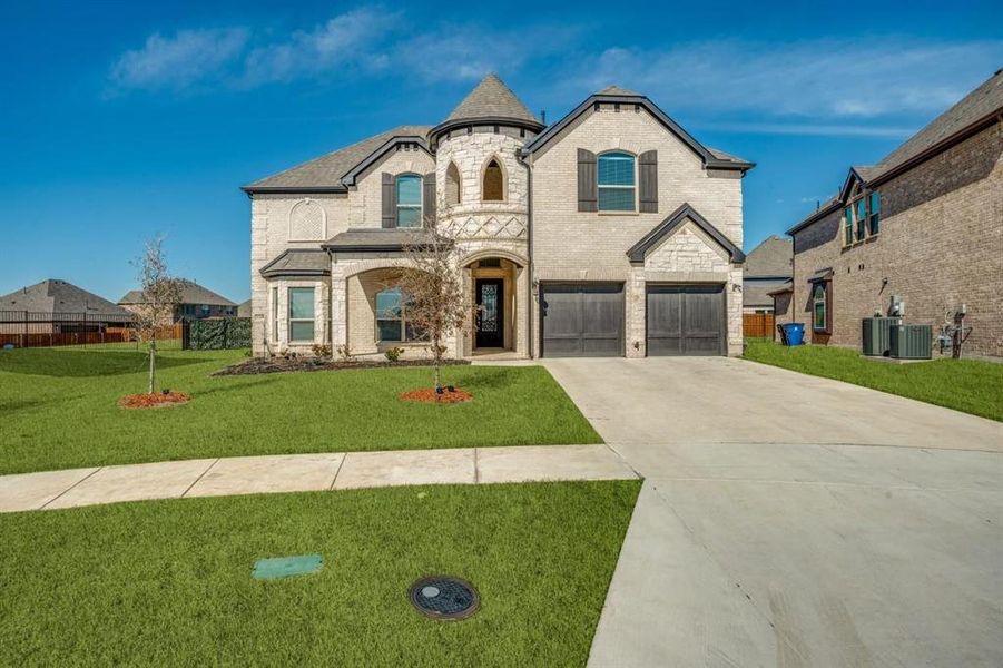 French provincial home featuring a front lawn and a garage