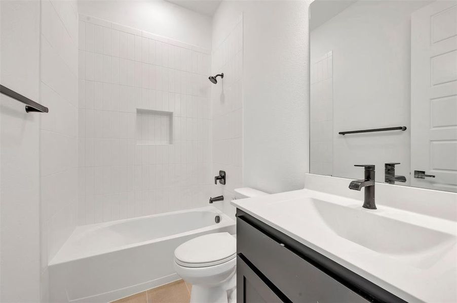 Contemporary bathroom featuring a white tile shower surround with a recessed niche, a white bathtub, and a modern vanity with a dark cabinet base and integrated sink