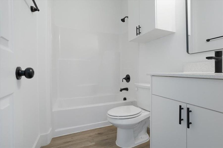 Full bathroom with hardwood / wood-style flooring, vanity, toilet, and shower / bath combination