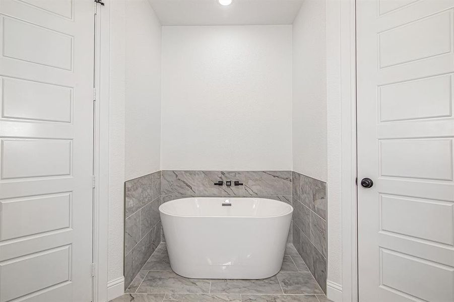 Full bathroom with tile walls, a freestanding tub, a wainscoted wall, and recessed lighting