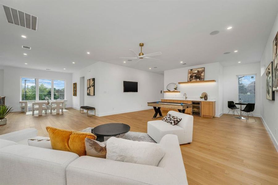 Living room featuring light wood-style flooring, recessed lighting, beverage cooler, and a ceiling fan Living room featuring light wood-style flooring, recessed lighting, beverage cooler, and a ceiling fan