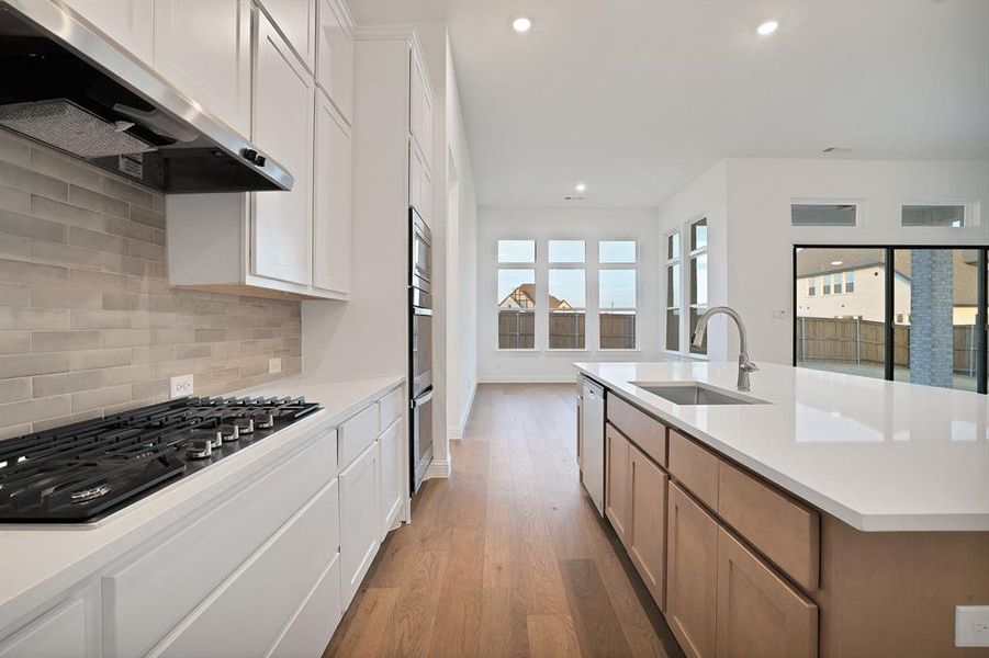 Kitchen featuring tasteful backsplash, a kitchen island with sink, white cabinetry, and appliances with stainless steel finishes