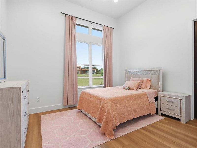 Room featuring a high vaulted ceiling, wood-finish flooring, and a large window with transom lites