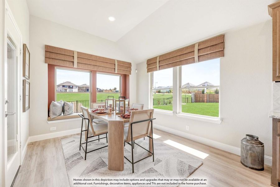 Bright dining nook with wood table, built-in bench seat, and large windows overlooking backyard