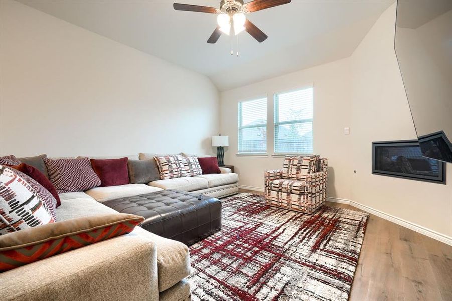 Living area featuring wood finished floors, vaulted ceiling, and ceiling fan Living area featuring wood finished floors, vaulted ceiling, and ceiling fan