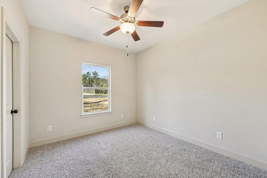 Comfortable secondary bedroom with plush carpet flooring and a ceiling fan.