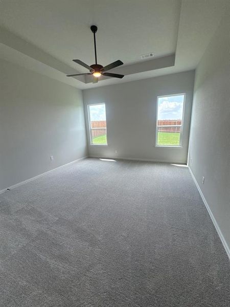 Spacious room with tray ceiling, contemporary ceiling fan, and grey carpet flooring