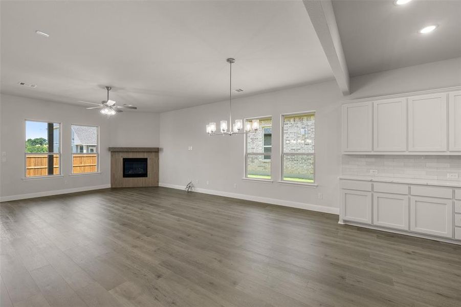 Unfurnished living room with ceiling fan, dark wood finished floors, beam ceiling, a glass covered fireplace, and recessed lighting Unfurnished living room with ceiling fan, dark wood finished floors, beam ceiling, a glass covered fireplace, and recessed lighting