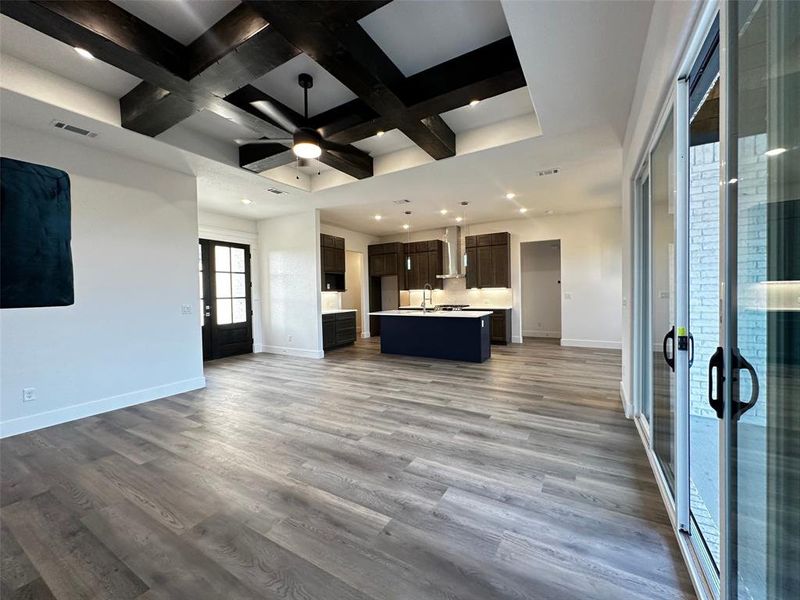 Unfurnished living room with baseboards, wood finished floors, visible vents, and coffered ceiling