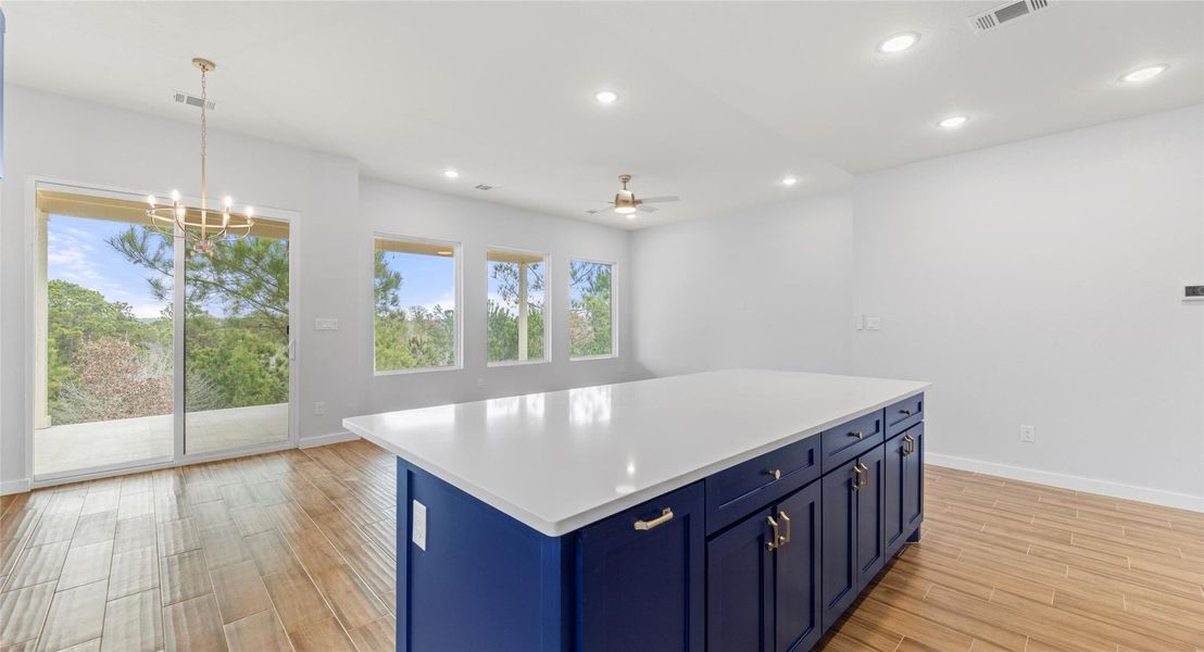 Kitchen featuring blue cabinets, hanging light fixtures, light wood-style floors, a ceiling fan, and recessed lighting