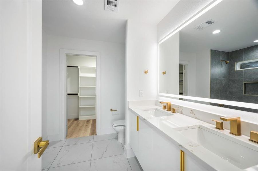 Bathroom featuring tiled shower, vanity, and toilet