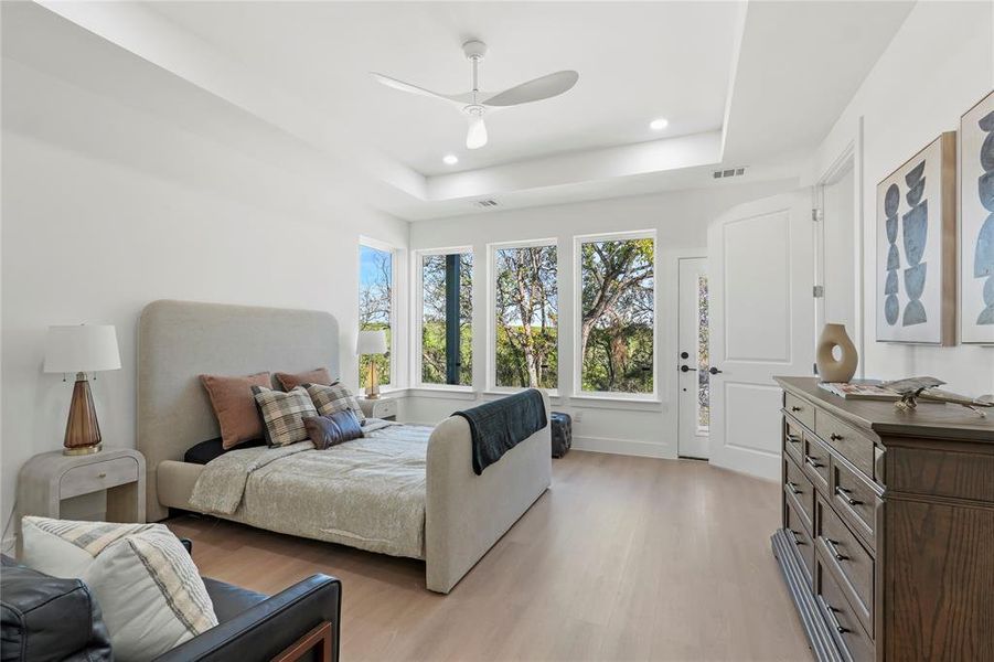 Bedroom featuring ceiling fan, access to outside, light wood-style floors, recessed lighting, and a raised ceiling