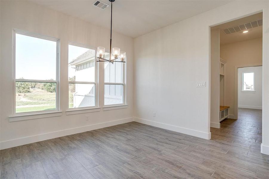 Unfurnished dining area with a notable chandelier, a healthy amount of sunlight, and light hardwood / wood-style flooring