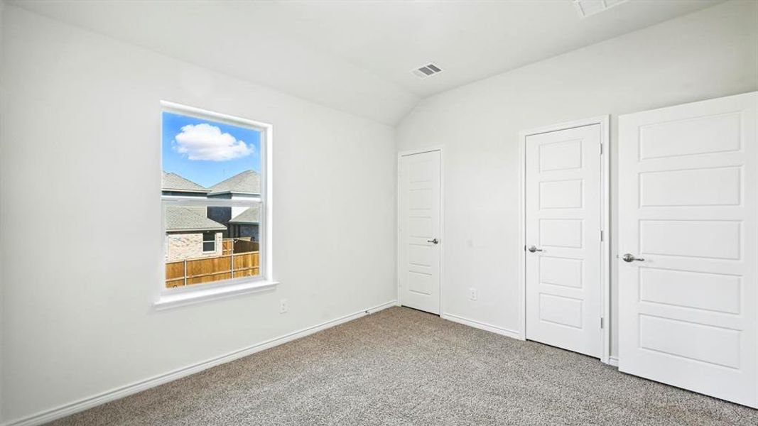 Unfurnished bedroom featuring lofted ceiling and carpet flooring