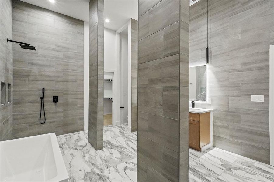 Bathroom with tile walls, shower with separate bathtub, vanity, and tile patterned floors