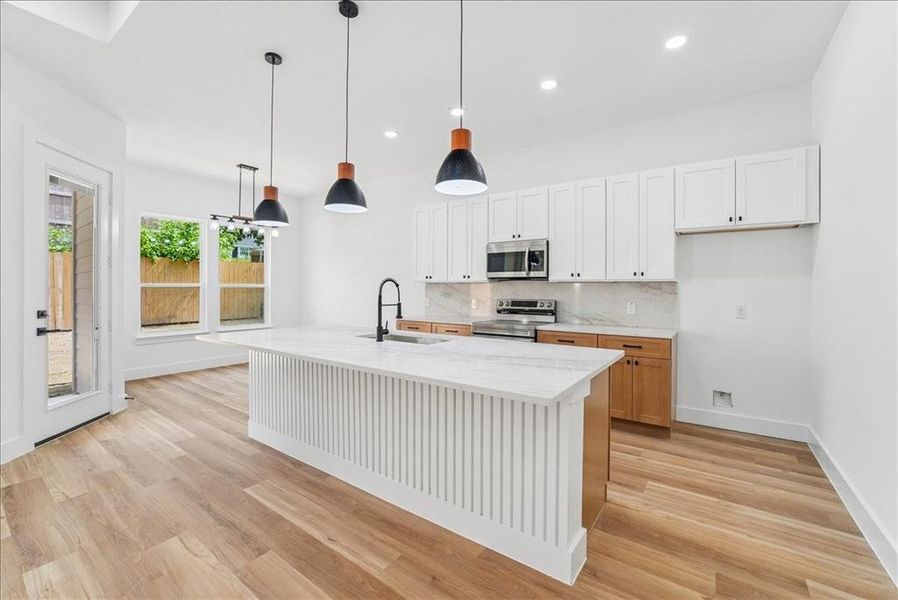 Modern kitchen featuring an expansive center island with a white fluted base and a light-toned countertop Modern kitchen featuring an expansive center island with a white fluted base and a light-toned countertop