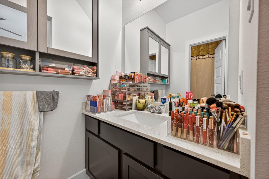 This photo showcases a bathroom vanity area with ample storage. The countertop is neatly organized with makeup and beauty products, indicating plenty of space for personal items. The modern cabinets and neutral color scheme provide a clean and functional design. This photo showcases a bathroom vanity area with ample storage. The countertop is neatly organized with makeup and beauty products, indicating plenty of space for personal items. The modern cabinets and neutral color scheme provide a clean and functional design.