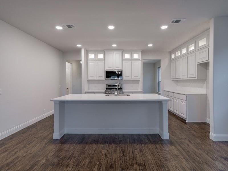 Kitchen with white cabinetry, sink, a kitchen island with sink, and dark wood-type flooring