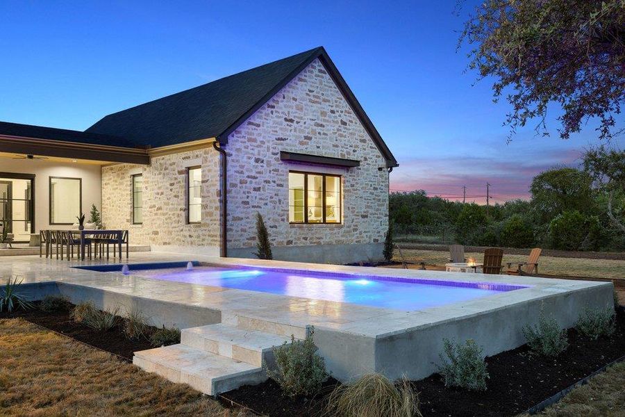 An inviting pool with integrated lighting complements this home's stone exterior and expansive patio.