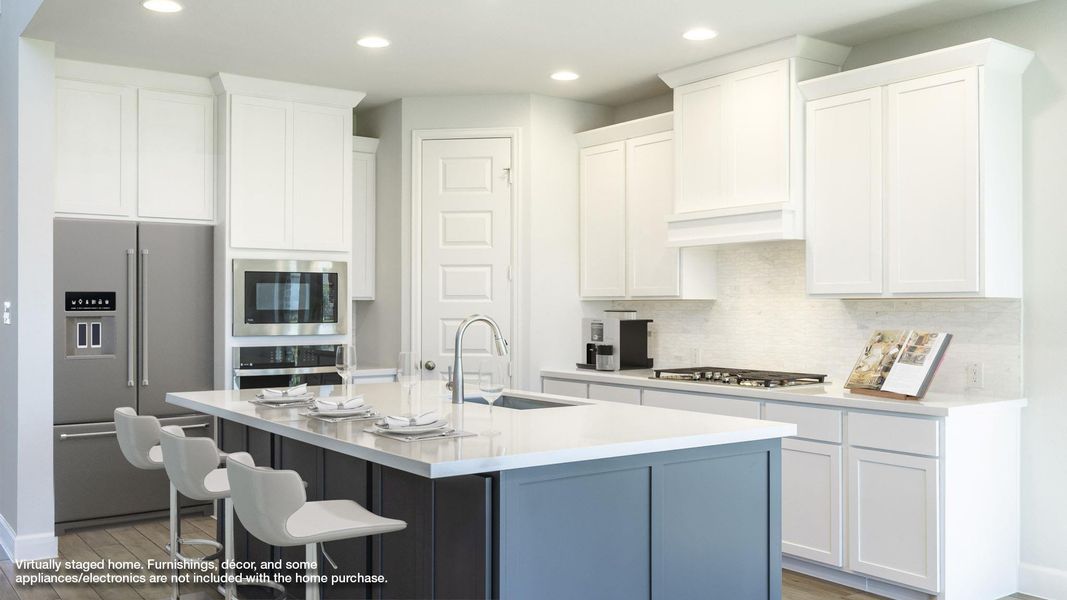 Kitchen featuring white cabinetry, appliances with stainless steel finishes, a kitchen bar, and a sink Kitchen featuring white cabinetry, appliances with stainless steel finishes, a kitchen bar, and a sink