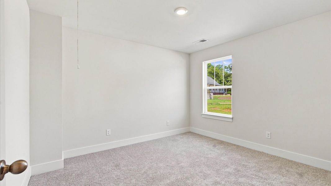Elegant bedroom retreat featuring soft carpet and oversized windows that create a bright, welcoming space