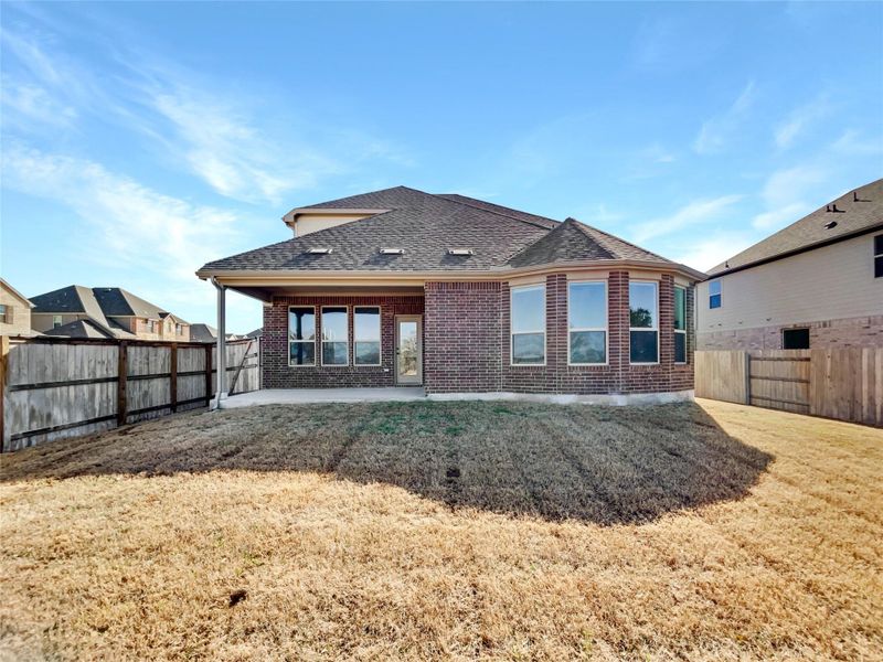 Rear view of house with a yard, a fenced backyard, a shingled roof, a patio area, and brick siding