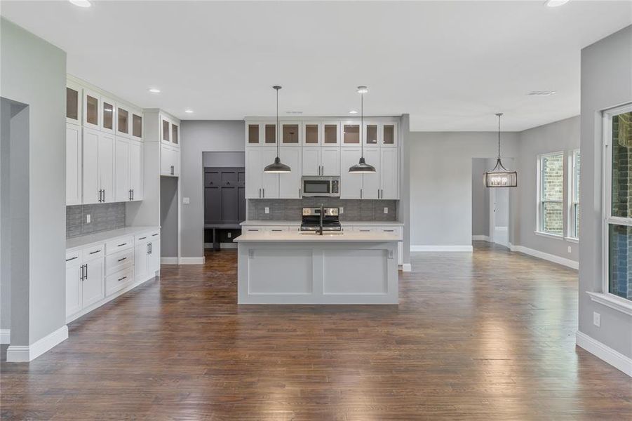 Kitchen featuring backsplash, glass insert cabinets, hanging light fixtures, recessed lighting, and appliances with stainless steel finishes Kitchen featuring backsplash, glass insert cabinets, hanging light fixtures, recessed lighting, and appliances with stainless steel finishes