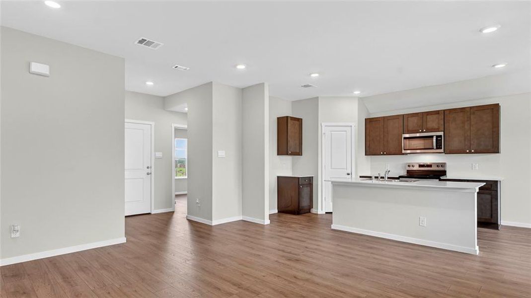 Open-concept living space featuring wood-finish flooring, recessed lighting, and a kitchen with dark wood cabinetry