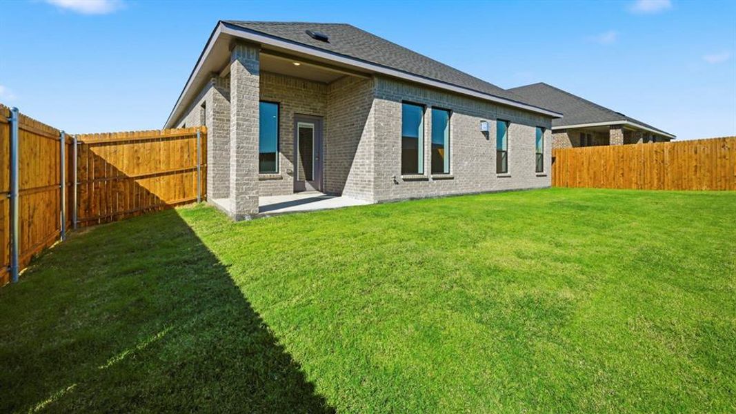 Back of property with a patio area, brick siding, a fenced backyard, and a shingled roof
