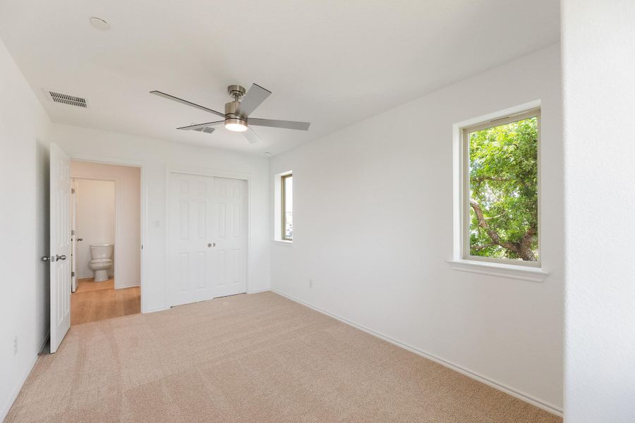 Unfurnished bedroom with light colored carpet, a closet, and a ceiling fan
