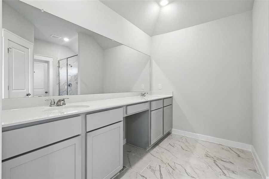 Full bathroom with a marble finish shower, double vanity, and marble look tiles