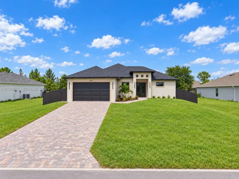 Single-story exterior featuring a paver driveway, attached two-car garage, and dark-toned privacy fencing