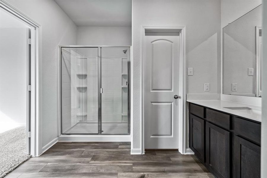 Bathroom featuring vanity, a shower with door, and wood-type flooring