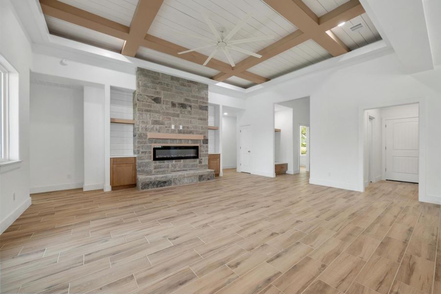 Living room with coffered ceiling, beam ceiling, wood finish floors, a ceiling fan, and a fireplace Living room with coffered ceiling, beam ceiling, wood finish floors, a ceiling fan, and a fireplace
