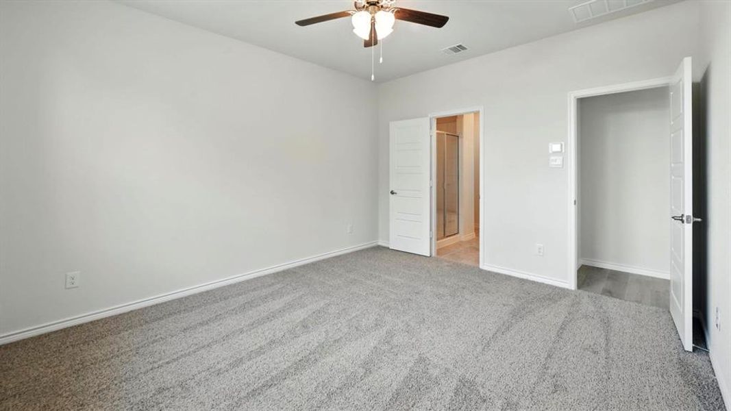 Unfurnished bedroom featuring carpet flooring, connected bathroom, and a ceiling fan