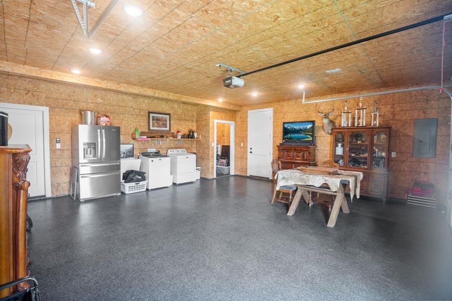Garage featuring electric panel, separate washer and dryer, a garage door opener, and stainless steel fridge with ice dispenser Garage featuring electric panel, separate washer and dryer, a garage door opener, and stainless steel fridge with ice dispenser