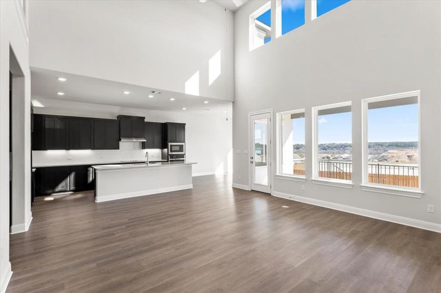 Unfurnished living room with plenty of natural light, dark wood-type flooring, and a high ceiling