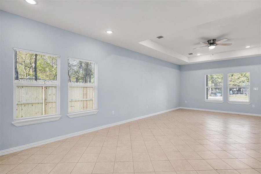 Empty room featuring ceiling fan, plenty of natural light, and light tile patterned flooring