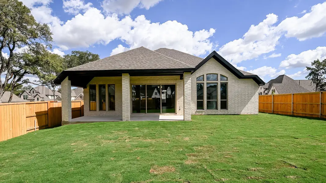 Rear view of house with a patio, a fenced backyard, brick siding, and roof with shingles