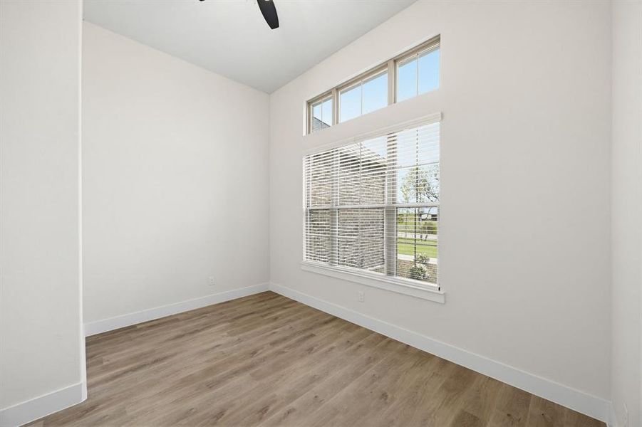 Bright interior space featuring a multi-pane window with transom lites, white window blinds, and wood-finish flooring