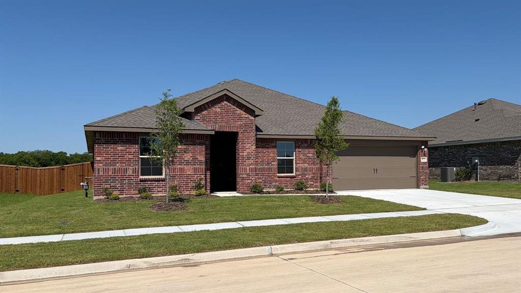 Brick exterior with a peaked roofline, an attached two-car garage, a concrete driveway, a manicured lawn, and a privacy fence along the property line Brick exterior with a peaked roofline, an attached two-car garage, a concrete driveway, a manicured lawn, and a privacy fence along the property line