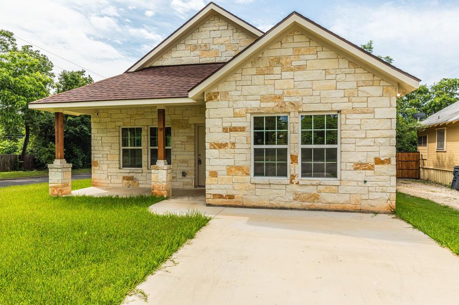 View of front of home with roof with shingles and stone siding